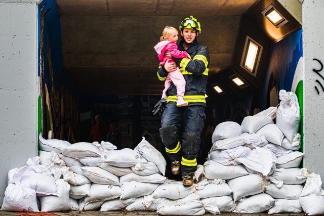 Hasič přenáší dítě přes protipovodňový val ze zaplaveného železničního podchodu v Bílovicích nad Svitavou na Brněnsku | foto: ČTK / Uhlíř Patrik